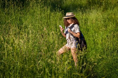 Sahada sırt çantalı bir kız telefona bakıyor. Akıllı telefondaki seyir subayı..