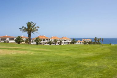 Atlantik Okyanusu yakınlarındaki lüks sahil otel tatil Golf Sahası. Yeşil çim sahası, palmiye ağaçları, ev, mavi gökyüzü ve okyanus