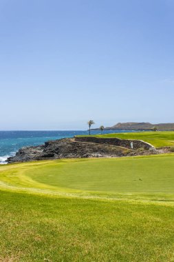 Yeşil golf sahası ve Atlantik Okyanusu dalgaları lüks sahil otel tatil. Yeşil çim sahası, palmiye ağaçları, mavi gökyüzü ve okyanus