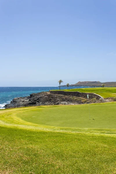 Yeşil golf sahası ve Atlantik Okyanusu dalgaları lüks sahil otel tatil. Yeşil çim sahası, palmiye ağaçları, mavi gökyüzü ve okyanus