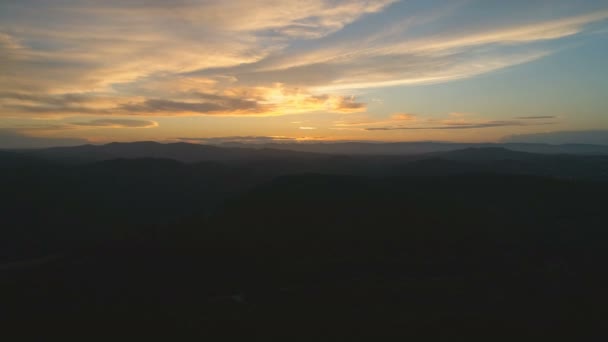 密な暗い山林にゆっくりと下って飛んでいく 雲と素晴らしいゴールデンアワーの夕日の美しい景色 空中映画4Kドローン映像 — ストック動画