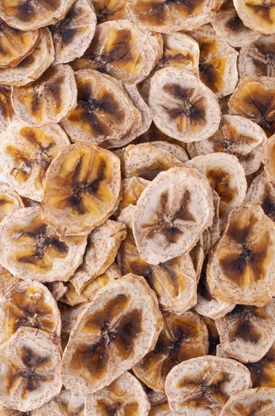Dried banana slices (chips) background. Dehydrated crispy fruit slices. Heap, pile of sun dried crunchy bananas. Healthy meal snack. Close up. Top view, view from above, flat lay. Isolated. Texture.