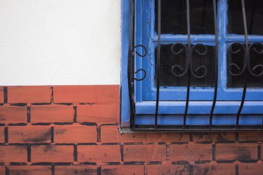 Bir kafes ile tuğla duvar ve mavi pencere