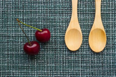 Olgun kiraz bir hasır arka plan ve iki tahta kaşıklar, yakın çekim