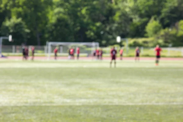 サッカー選手ぼけボケ味を持つ抽象的な背景の緑の芝生フィールド — ストック写真