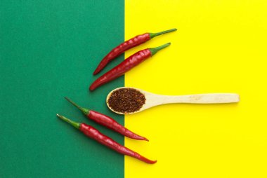 üstten görünüm, sarı-yeşil zemin üzerine bir tahta kaşıkla 4 kırmızı biber