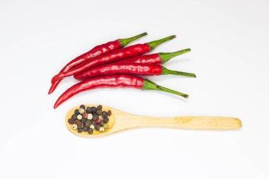 Yakın çekim üstten görünüm kırmızı biber biber beyaz zemin üzerine tahta kaşık ile