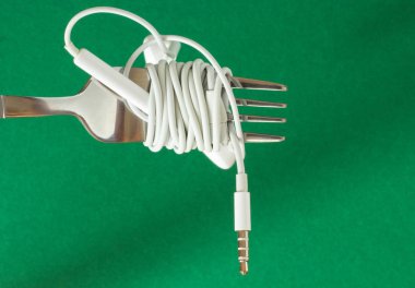 Beyaz kulaklık ve çatal yeşil bir arka plan üzerinde yakın çekim