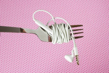 Beyaz kulaklık ve çatal ile polka dotsd, pembe bir arka plan üzerinde yakın çekim