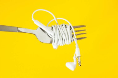 Beyaz kulaklık ve sarı bir arka plan üzerinde çatalı