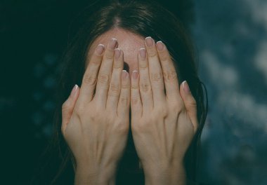 Kız yüzünü elleriyle tonda fotoğraf kapsar.