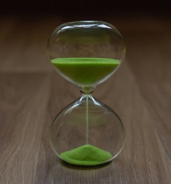 Yakın çekim, kum saati üzerinde bir ahşap arka plan bulanık.