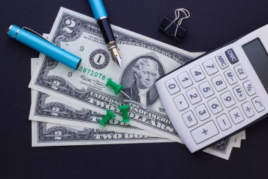 Hesap makinesi, ofis malzemeleri ve dolar siyah bir arka plan iş kavramı