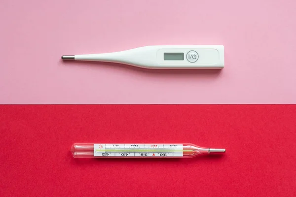 Old and modern thermometer on a pink and red background