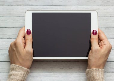 Bir tablet bir ahşap zemin arka plan üzerinde tutan kız