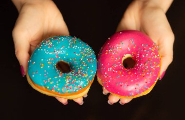 Tatlı çörek sprinkles ile siyah arka plan üzerinde tutan eller yakın çekim