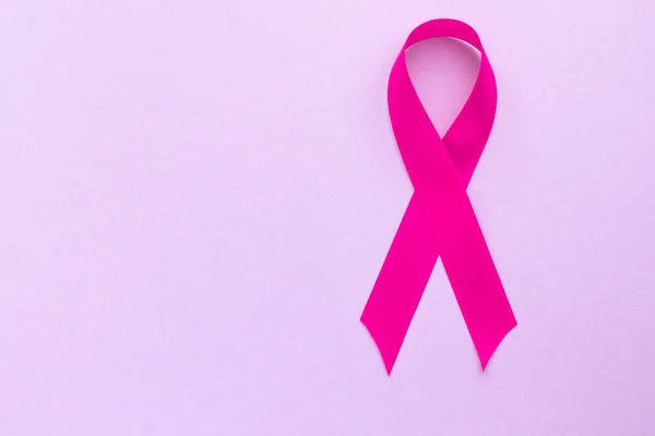 Pink ribbon on a purple background, the concept of female health, the fight against breast cancer