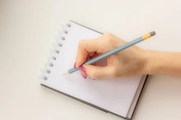 Γυναικείο Χέρι Κρατά Ένα Μολύβι Και Γράφει Ένα Σημειωματάριο — Φωτογραφία Αρχείου