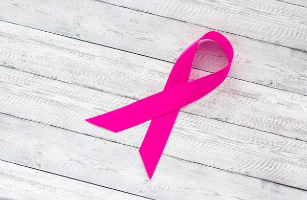 Concept of female health, pink ribbon on a background of wood, breast cancer and the fight against it