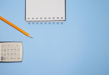 Not defteri, hesap makinesi ve kalem mavi arka plan, üstten görünüm