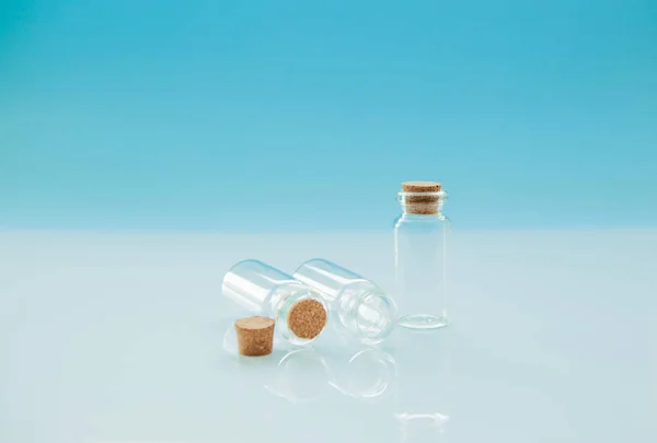 Empty little bottles with cork stopper on light blue background, close-up