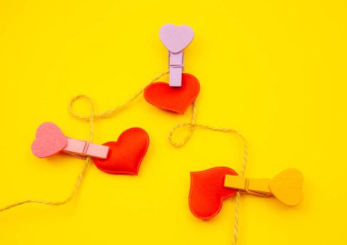 Kırmızı kalpler ve sarı zemin üzerine clothespin. Sevgililer ve 8 Mart anne kadın gün kavramı