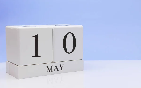 May 10st. Day 10 of month, daily calendar on white table with reflection, with light blue background. Spring time, empty space for text