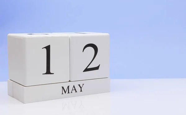 May 12st. Day 12 of month, daily calendar on white table with reflection, with light blue background. Spring time, empty space for text