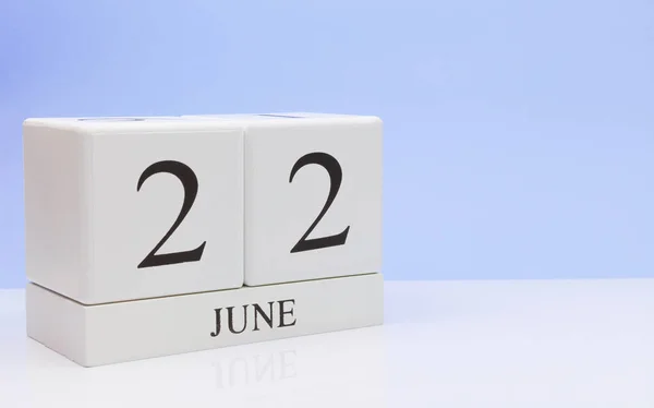 June 22st. Day 22 of month, daily calendar on white table with reflection, with light blue background. Summer time, empty space for text