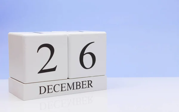 December 26st. Day 26 of month, daily calendar on white table with reflection, with light blue background. Winter time, empty space for text