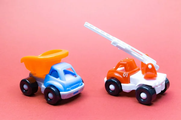 五颜六色的玩具卡车和消防车在粉红色的背景 — 图库照片