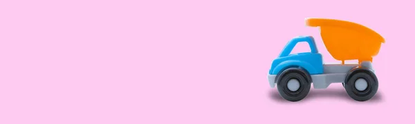 Іграшкова вантажівка на рожевому тлі, простір для тексту, концепція будівельних робіт або дитячої гри — стокове фото