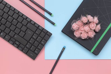 Üst görünüm, mavi ve pembe arka plan üzerinde klavye ile çiçek ve kalem ile dizüstü bilgisayar. Düz döşeme stili