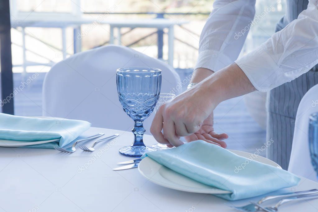 Restaurant waiter serves a table for a wedding celebration, close-up
