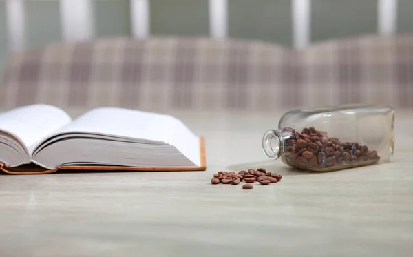 Libro abierto sobre la mesa blanca y granos de café, concepto de educación — Foto de Stock