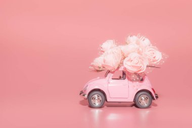 Pembe arka plan üzerinde beyaz Güller buketi ile pembe retro oyuncak araba. Konsept Sevgililer Günü, 14 Şubat kartı, 8 Mart, Dünya Mutlu Kadınlar Günü