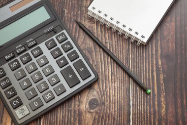 Not defteri ve kalem ile ahşap arka plan üzerinde Hesap makinesi, iş kavramı ve tasarruf finansmanı