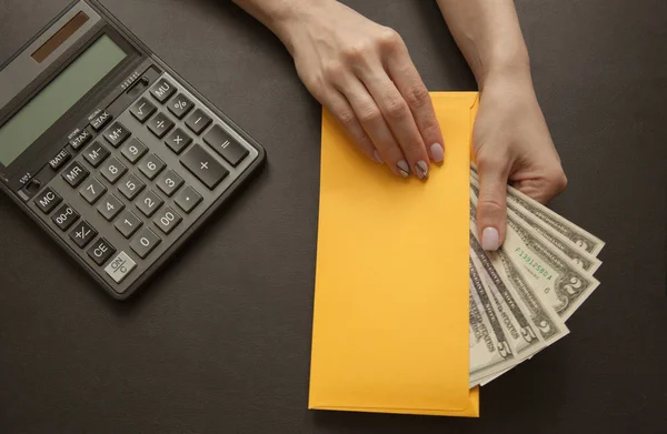 The concept of financial well-being, the girl in her hand holds a yellow envelope with money. Top view.