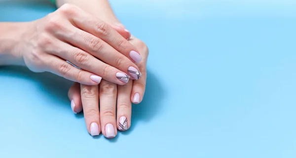 Mãos macias com manicure nu perfeito no fundo azul pastel na moda. conceito de mãos saudáveis e bonitas . — Fotografia de Stock
