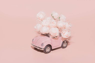 Pembe arka plan üzerinde beyaz Güller buketi ile pembe retro oyuncak araba. Konsept Sevgililer Günü, 14 Şubat kartı, 8 Mart, Dünya Mutlu Kadınlar Günü