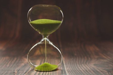 Kum saati iş tarihi, aciliyet ve zaman tükenme konsepti, ahşap arka planda zaman geçen.