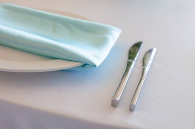 Turkuaz peçete, metal çatal, bıçak ve masa.