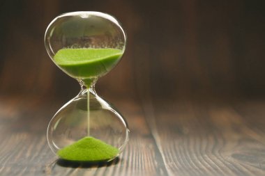 Bir cam ampul içinde düşen kum ile Kum Saati, metin için alan ile ahşap bir arka plan üzerinde zaman geçen veya kayıp zaman