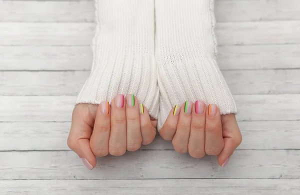 Veelkleurige moderne manicure, nagel ontwerp, zomer stemming, handen in een witte trui top uitzicht — Stockfoto
