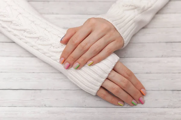 Multicolored modern manicure, nail design, summer mood, hands in a white sweater — Stock Photo, Image