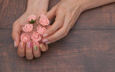 Kırmızı ahşap arka planda modern manikür ve pembe çiçekler ile güzel kadın elleri