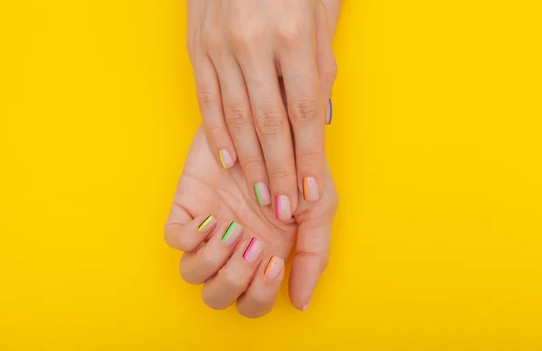 Elegante manicure feminina na moda. As mãos da bela jovem mulher no fundo amarelo . — Fotografia de Stock