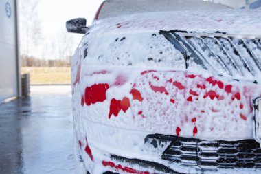 Araba temizliği. Kırmızı arabayı sabunla yıka. Yüksek basınçlı su yıkama yakın çekim