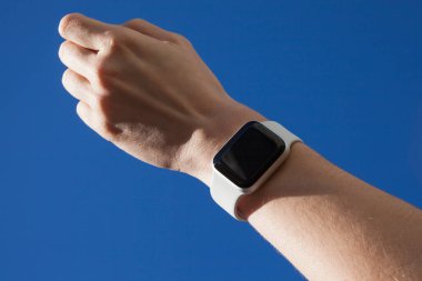 Mavi gökyüzü nün arka planında akıllı saatli kadın eli