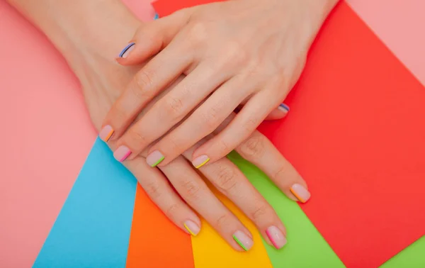 Modern stylish manicure rainbow or summer mood, on a pink table with color envelopes